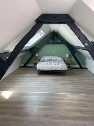 Cette chambre mansardée comprend un lit et deux tables. dans l'établissement Corps de ferme charmant Amiens avec Parking, à Ferrières