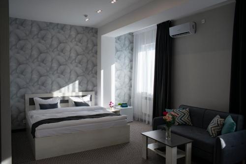 um quarto com uma cama e um sofá em Tengri Hotel em Aktau