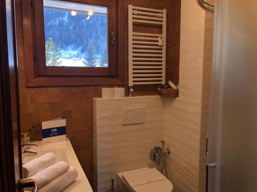 a bathroom with a sink and a toilet and a window at House Edelweiss by Holiday World in La Thuile