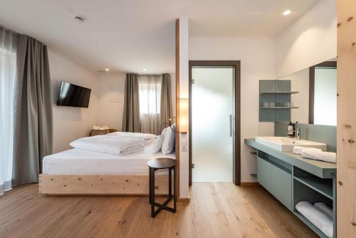 a bedroom with a bed and a sink and a mirror at Hotel Bewaller in Obereggen