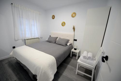 a white bedroom with a bed and a window at APARTAMENTOS LUDOVICO in Béjar