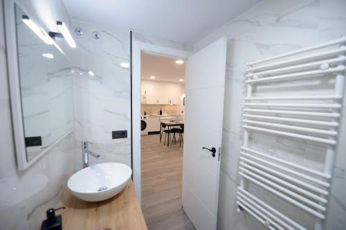 Baño blanco con lavabo y espejo en APARTAMENTOS LUDOVICO, en Béjar