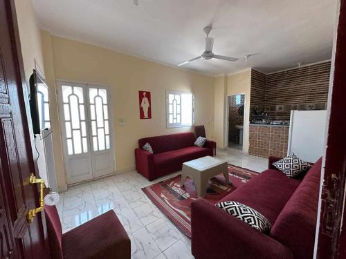 Skylen Hostel في الغردقة: غرفة معيشة مع أريكة حمراء وطاولة