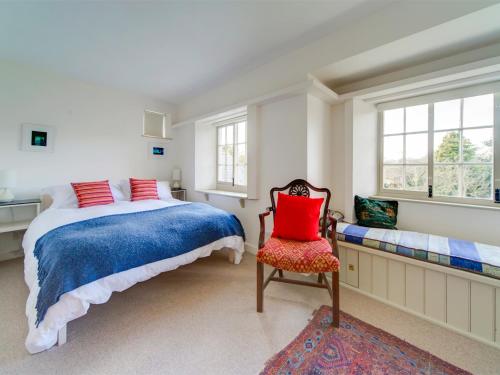 a bedroom with a bed and a chair and windows at 4 Bed in Isle of Purbeck IC177 in Corfe Castle