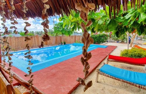a swimming pool with a thatched roof and a resort at Villa Francesca Boutique Hotel in Uroa
