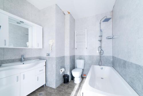 a bathroom with a tub and a toilet and a sink at Grand Noel Bakuriani in Bakuriani