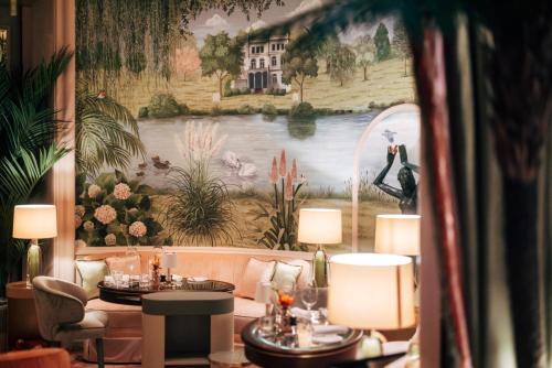 a living room with two tables and a large painting at Fairmont Hotel Vier Jahreszeiten in Hamburg