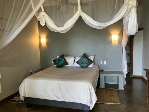 a bedroom with a white bed with blue pillows at Casa Jardim in Vilanculos