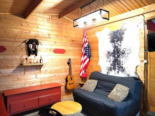 Zimmer mit einem Bett und einer Gitarre in einer Hütte in der Unterkunft Chalet Opale Texas in Hermelinghen