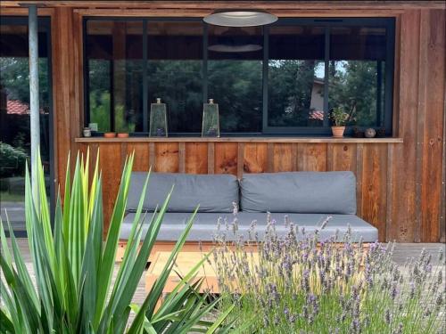 - un canapé installé devant un bâtiment avec fenêtres dans l'établissement Charmant Chalet au bord du lac, à Lacanau