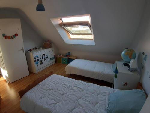 um quarto com 2 camas e uma clarabóia em Maison au calme, dans le village d'Erdeven em Erdeven