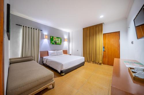 a hotel room with a bed and a couch at Spazzio Bali Hotel in Legian