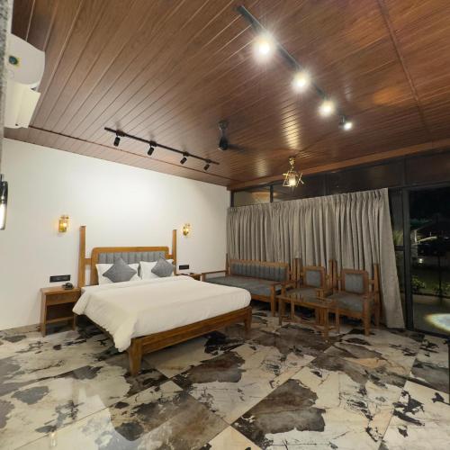 a bedroom with a bed and two chairs in it at White Sand Beach Resort in Kondivli