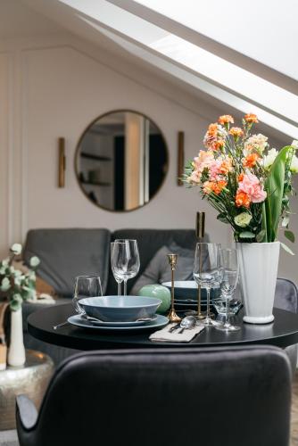 a table with a plate and glasses and flowers on it at Central Palace - LoftAffair Collection in Kraków