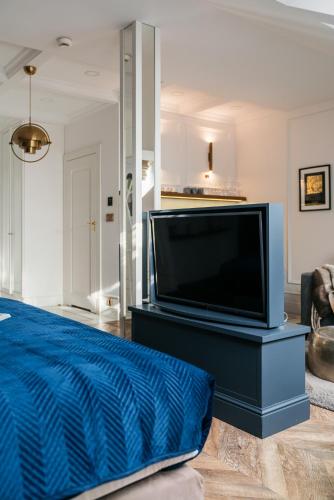 a living room with a tv and a blue bed at Central Palace - LoftAffair Collection in Kraków