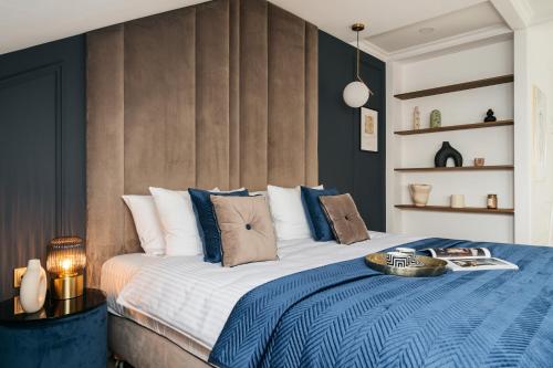 a bedroom with a large bed with blue and white pillows at Central Palace - LoftAffair Collection in Kraków