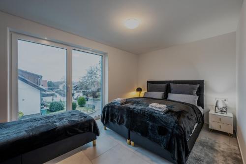 1 dormitorio con 2 camas y ventana grande en EXQUIS Luxus Apartment USM I Kamin I Terrasse I Parkplatz I Mercedes en Böblingen