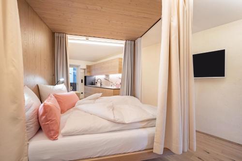 a bedroom with a bed with white sheets and pink pillows at Avia Living Anna in Brunico