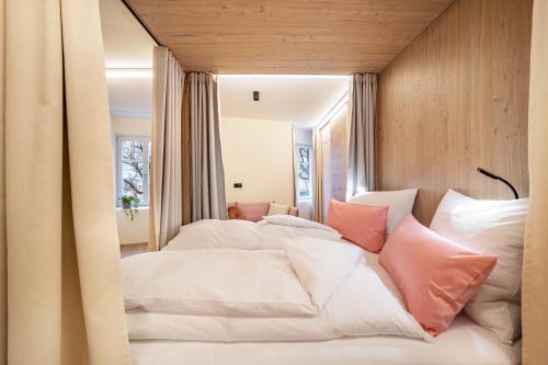 una camera da letto con un grande letto bianco con cuscini rosa di Avia Living Anna a Brunico