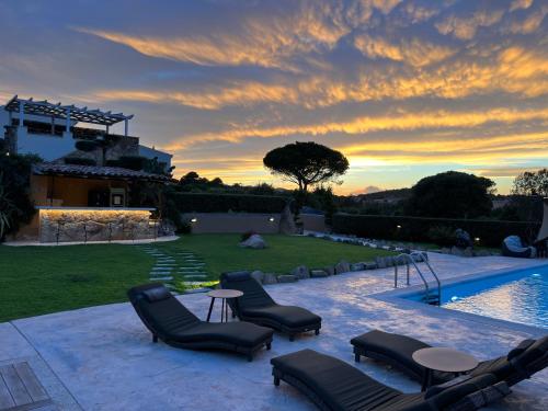 a backyard with chairs and a swimming pool at sunset at Antica Fonte Holiday Homes in San Pantaleo
