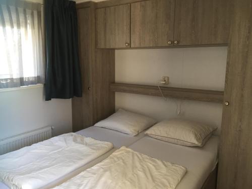 two twin beds in a room with a window at Meerchalets in Biggekerke
