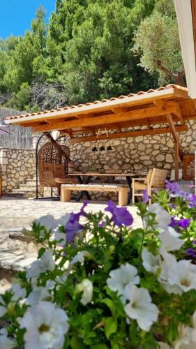 a picnic table and flowers in front of a stone wall at Rania Apartments in Agios Nikitas