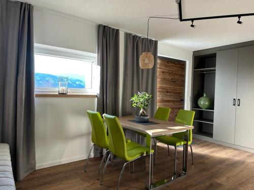 a dining room with a table and green chairs at Dolomitenblick Suite in Stronach