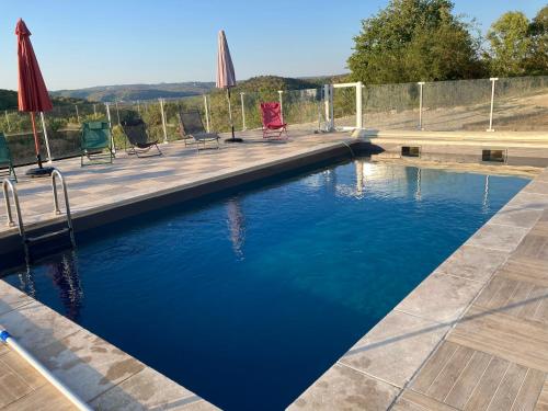 Una piscina con sillas y sombrillas en un patio. en Le Domaine des Ramonets, en Cahors