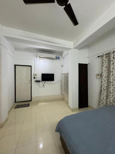 a bedroom with a bed and a flat screen tv at La Belleza Guesthouse in Guwahati