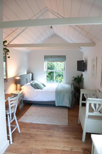 a bedroom with a bed and a desk and a window at Mulberry Studio in Hawkhurst
