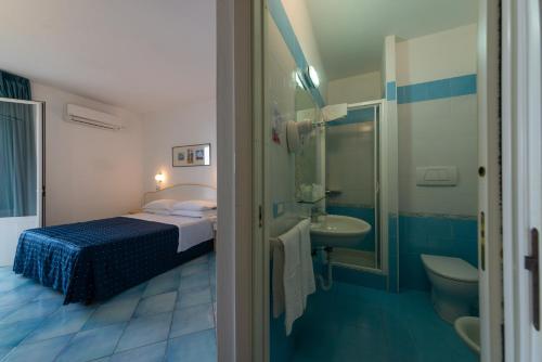 a bedroom with a bed and a sink and a toilet at Hotel Villa Ireos in Ischia