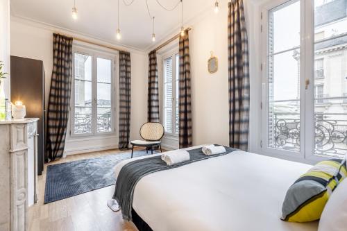 une chambre avec un grand lit et deux fenêtres dans l'établissement Sweett - Lescot, à Paris