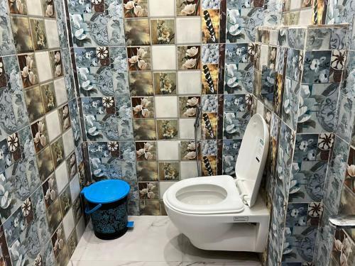 a bathroom with a toilet and a tiled wall at Nidhivan Dhaam in Mathura