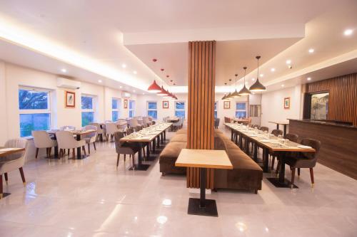 un restaurante con mesas largas, sillas y ventanas en Landmark Bhairahawa en Bhairāhawā