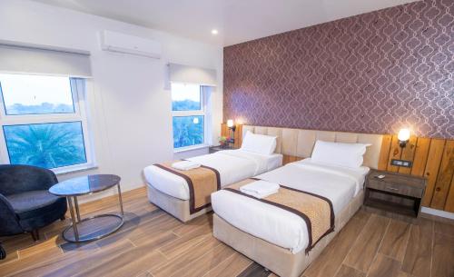 una habitación de hotel con 2 camas y una silla en Landmark Bhairahawa en Bhairāhawā