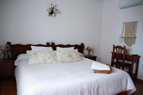 a bedroom with a white bed with a basket on it at Hostal Rural La Plata Parking Incluido in Arcos de la Frontera