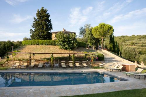 パニカーレにあるAgriturismo Poggio del Peroの背景に家があるプール(椅子付)