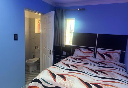 a blue bedroom with a bed and a bathroom at Goldwel Lodge in Kempton Park