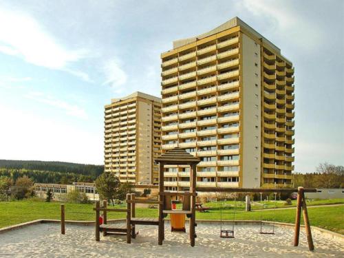 a park with two benches and a large building at Apartment Walpurgis mit toller Aussicht & Schwimmbad in Hohegeiß