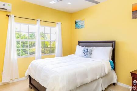 a bedroom with a white bed with a window at Charming Guest House near Chalk Sound and the Beach in Providenciales