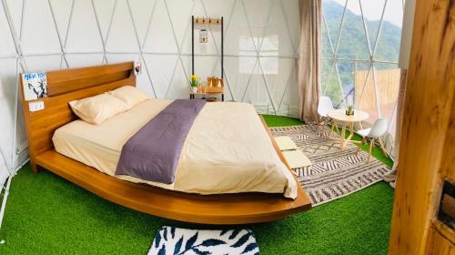 um quarto com uma cama num quarto com relva verde em Tham Ma Chard ทำมะชาด em Ban Ko Doi Tung