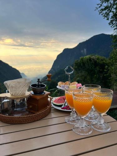 two glasses of orange juice on a table with a view at Tham Ma Chard ทำมะชาด in Ban Ko Doi Tung