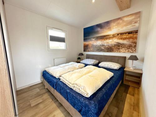 a bedroom with a bed and a painting on the wall at Chalet 5a op Recreatiepark De Wielen in Sint Maarten