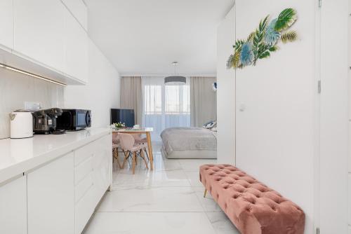a white kitchen with a bench in a room at Sunrise Apartment with Balcony & Wellness Zone by Rent like home in Międzyzdroje