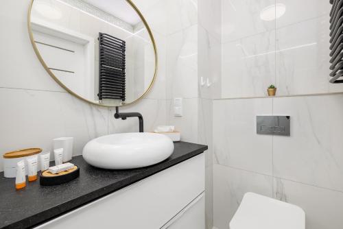 a white bathroom with a sink and a mirror at Sunrise Apartment with Balcony & Wellness Zone by Rent like home in Międzyzdroje