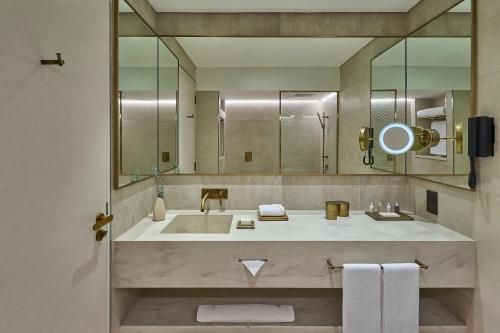 a bathroom with a sink and a large mirror at ERTH Abu Dhabi Hotel in Abu Dhabi