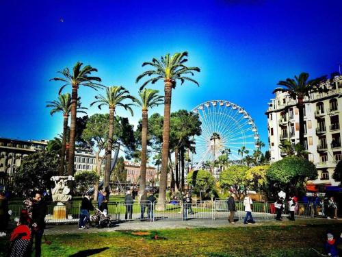 a park with palm trees and a ferris wheel at Villa Reine in Nice