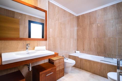 a bathroom with a sink and a toilet and a mirror at Jardines de Niza in Jávea