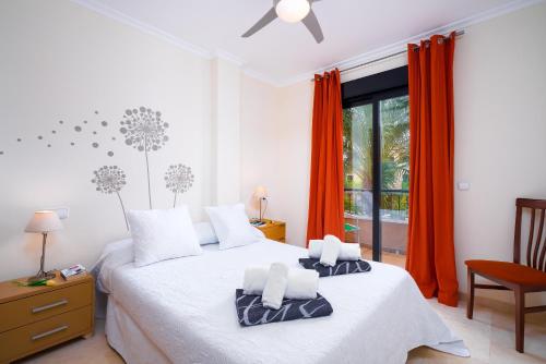 1 dormitorio con 2 camas y una ventana con cortinas de color naranja en Jardines de Niza, en Jávea