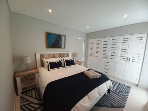 a bedroom with a large bed with black and white pillows at Queens Cove One Bedroom Apt 2 in Knysna